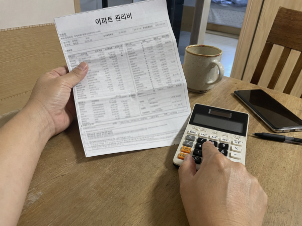 아파트 관리비 고지서를 확인하며 지출 항목을 계산하는 모습